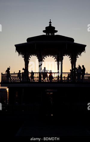 Silhouettes of people dancing cuban salsa on bandstand at sunset by sea, Hove, East Sussex, UK Stock Photo