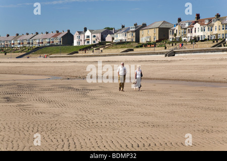 A retired couple walk on the beach at Newbiggin-by-the-Sea in Northumberland, England. Stock Photo