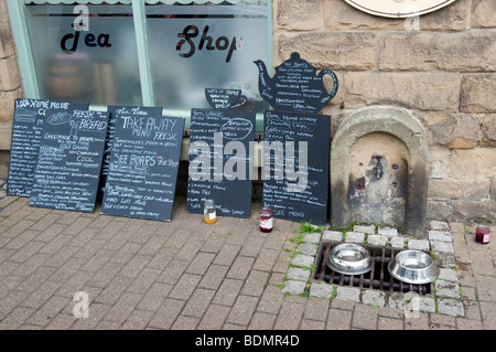 'Menu boards' and tap with metal dog watering bowls outside a 'Tea Shop' Stock Photo