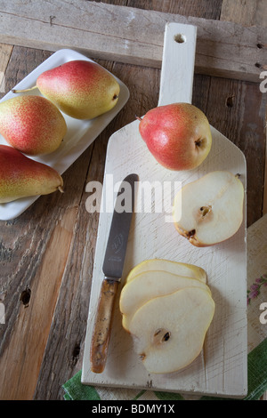 Pears [Forelle]  whole and sliced on a white chopping board with a knife Stock Photo