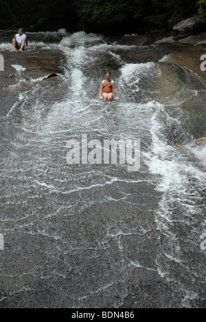 A young person slides down a flat rock water slide in North Carolina. Stock Photo