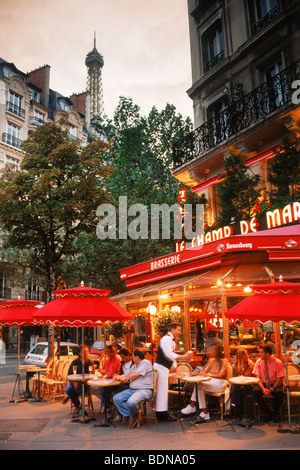 Le Champ De Mars Restaurant with patrons on Ave de la Bourdonnais in Paris under Eiffel Tower at dusk Stock Photo