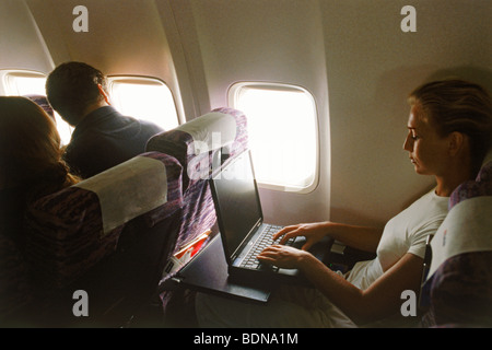 Female passenger using laptop during flight Stock Photo