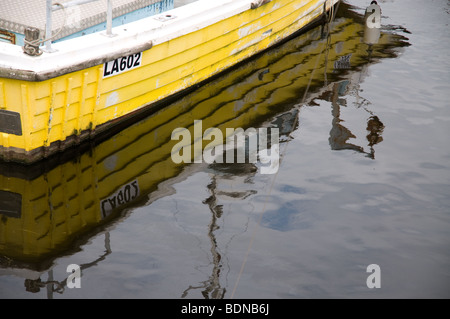 Crop of a yellow boat with it's reflections in Swansea marina. Stock Photo