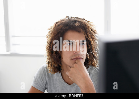 Young man using computer sitting at desk Stock Photo