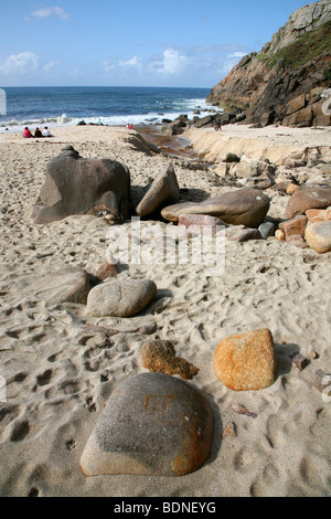 People relaxing on the beach of a sandy cove on the rocky coast near the lighthouse at  Pendeen, a village on the north Cornish Stock Photo