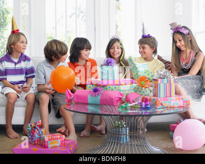 Group of children (7-12) sitting on sofa at birthday party Stock Photo