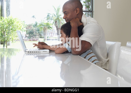 Father and son (5-6 years) using laptop in dining room, side view Stock Photo