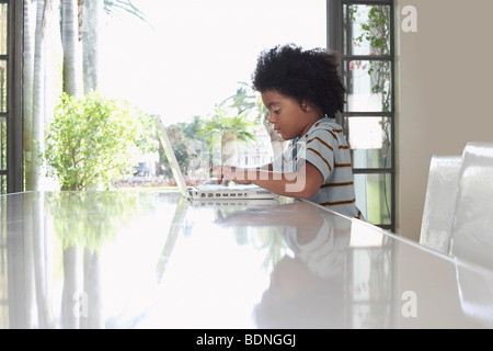 Boy (5-6 years) using laptop in dining room, side view Stock Photo