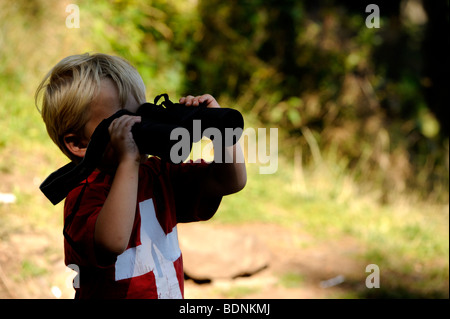 Young boy looking through binoculars outdoors Stock Photo