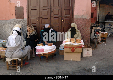 Poor Veiled Moroccan Arabic Muslim Women Selling Traditional Flatbread, Flat bread or Bread on the Street in Marrakesh, Morocco Stock Photo