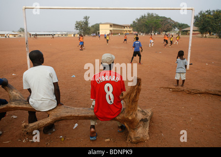 Man wearing Liverpool shirt watches Football practice. Corners Babies Youth Football Academy . Kumasi. Ghana. Stock Photo