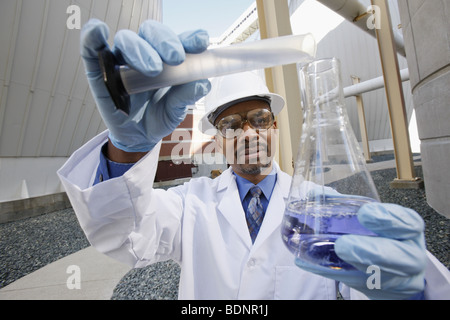 Scientist pouring liquid into a flask from a graduated cylinder Stock Photo