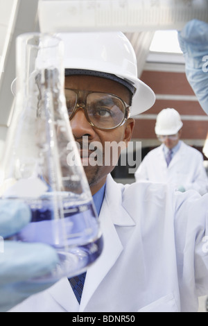 Scientist pouring liquid into a flask from a graduated cylinder Stock Photo