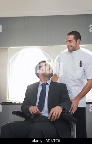 Barber talking to customer in barber shop Stock Photo