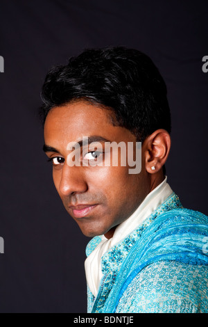 Beautiful face of an Indian Hindu young man with earing wearing blue Dhoti. Portrait of handsome Desi male, isolated. Stock Photo