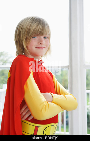 Portrait of boy (7-9) with arms crossed wearing superhero costume, smiling