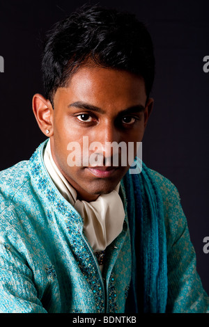 Beautiful face of an Indian Hindu young man with earing wearing blue Dhoti. Portrait of handsome Desi male, isolated. Stock Photo