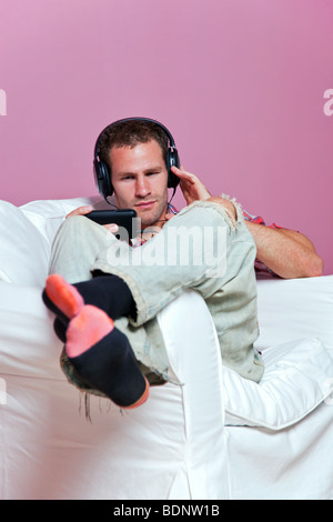 Relaxed male sitting listening to music on his mp3 player Stock Photo