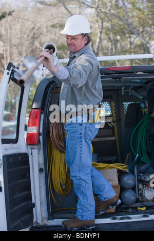 Plumber taking out a copper pipe from his truck Stock Photo