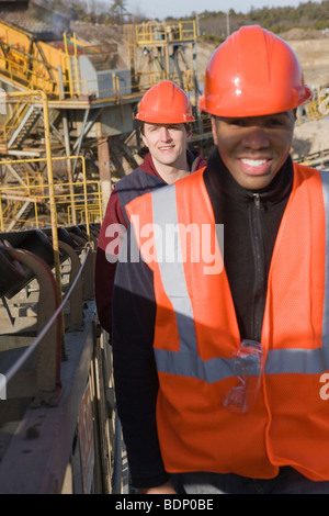 Two engineers on a conveyor belt at a construction site Stock Photo