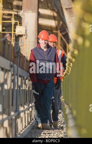 Two engineers standing on a conveyor belt at a construction site Stock Photo