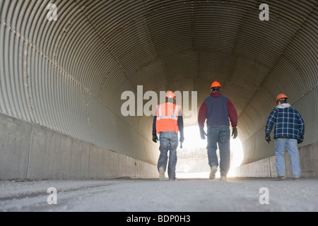 Three engineers walking in a tunnel Stock Photo
