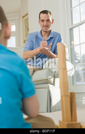 Man signing the word 'Help' in American Sign Language while communicating with his son Stock Photo