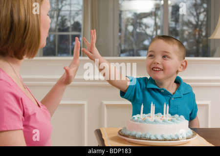 Woman signing the number '5' in American Sign Language while communicating with her son Stock Photo