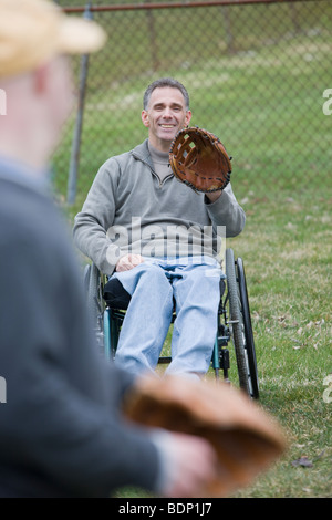 Disabled man playing baseball with his son Stock Photo