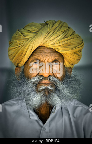 India, Rajasthan, Jodhpur, older Rajasthani Indian man with bushy gray beard wearing yellow turban Stock Photo