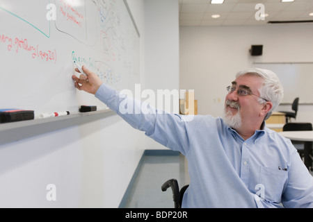 University professor writing on a whiteboard in a classroom Stock Photo