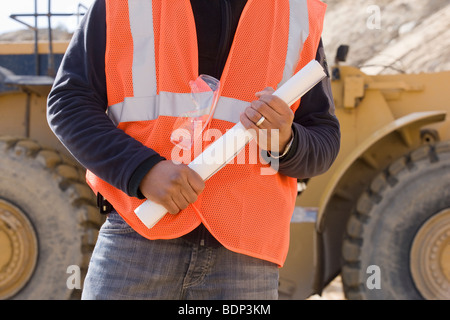 Engineer holding a blueprint at a construction site Stock Photo