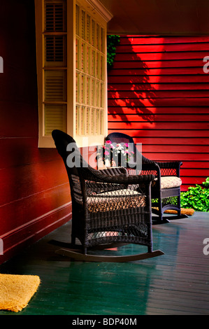 An American front porch with wooden boarding and two whicker rocking chairs Stock Photo