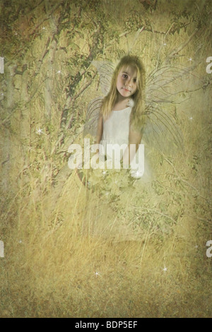 young fairy child standing in a golden field with flowers Stock Photo