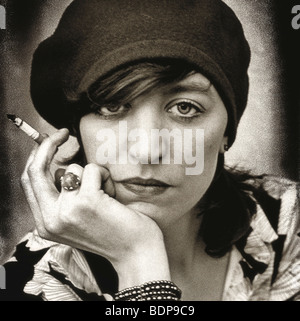Close up of a middleaged woman wearing a hat and smoking a cigarette looking sternly at the camera Stock Photo
