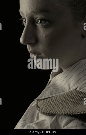 A young woman wearing a striped shirt and tie looking apprehensive Stock Photo