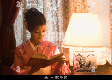 Young woman in kimono reading book Stock Photo