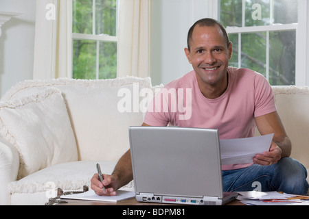 Hispanic man sorting out bills in front of a laptop Stock Photo