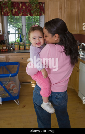 Hispanic woman carrying her daughter Stock Photo