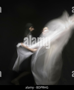 A young woman moving with a veil of white fabric in a blur Stock Photo