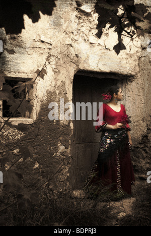 A young Spanish woman wearing traditional Flamenco dress standing in a doorway to an old building Stock Photo