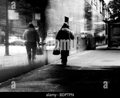 A man walking along a street carrying a bag Stock Photo