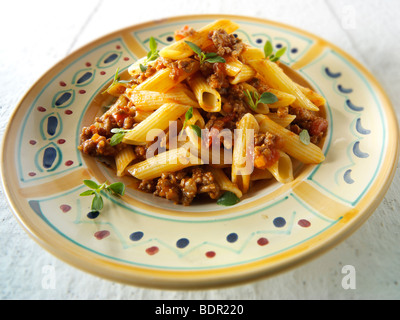 Fresh cooked pene and bolognese ragout served on a plate in a table setting. Serving suggestion Stock Photo