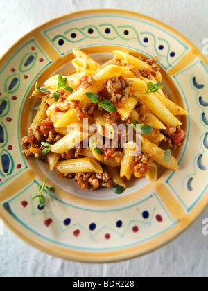 Top shot of Fresh cooked pene and bolognese ragout served on a plate in a table setting. Serving suggestion Stock Photo