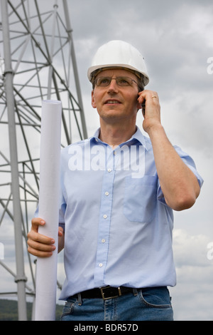 Engineer with plan in his hand talking on cell phone on construction side Stock Photo