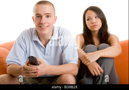 Junger Mann schaut begeistert fern, w hrend seine Freundin neben ihm genervt auf dem Sofa sitzt Stock Photo