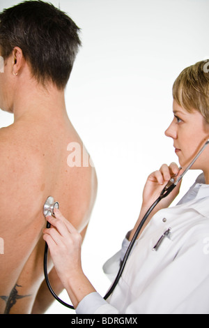 Female doctor using a stethoscope at a male patient Stock Photo