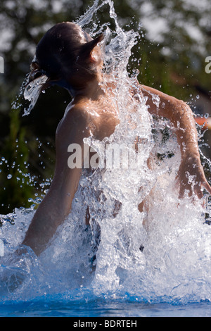 Teenage boy splashing around the water in the pool. Stock Photo