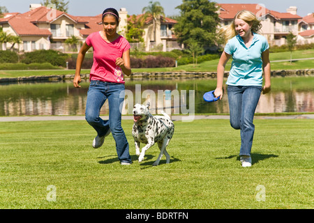 United States Hispanic caucasian girls 11-13 years old year hanging out run dog owner children fun child playing play plays dog front view MR  © Myrleen Pearson Stock Photo